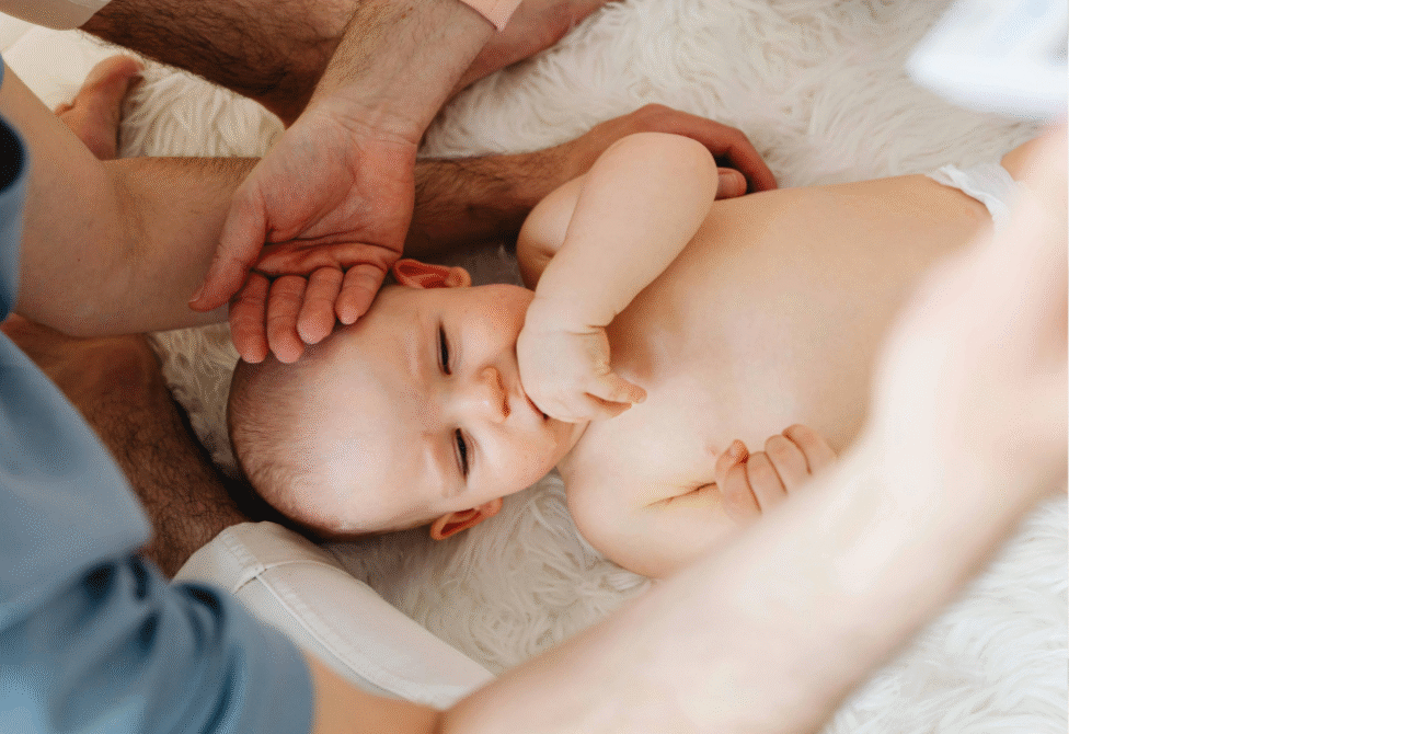 An infant lies on his back while two bodywork practitioners assess his sensory processing ability.