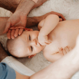 An infant lies on his back while two bodywork practitioners assess his sensory processing ability.